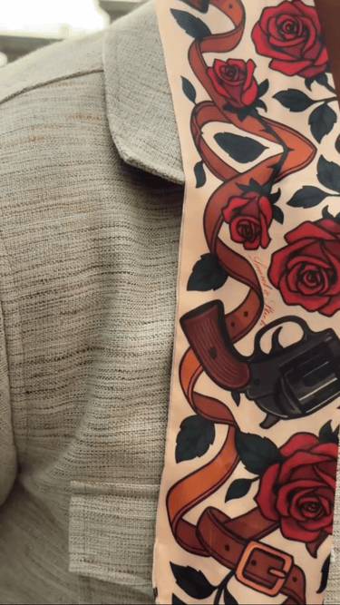 Scarf with guns and roses design on a gray jacket