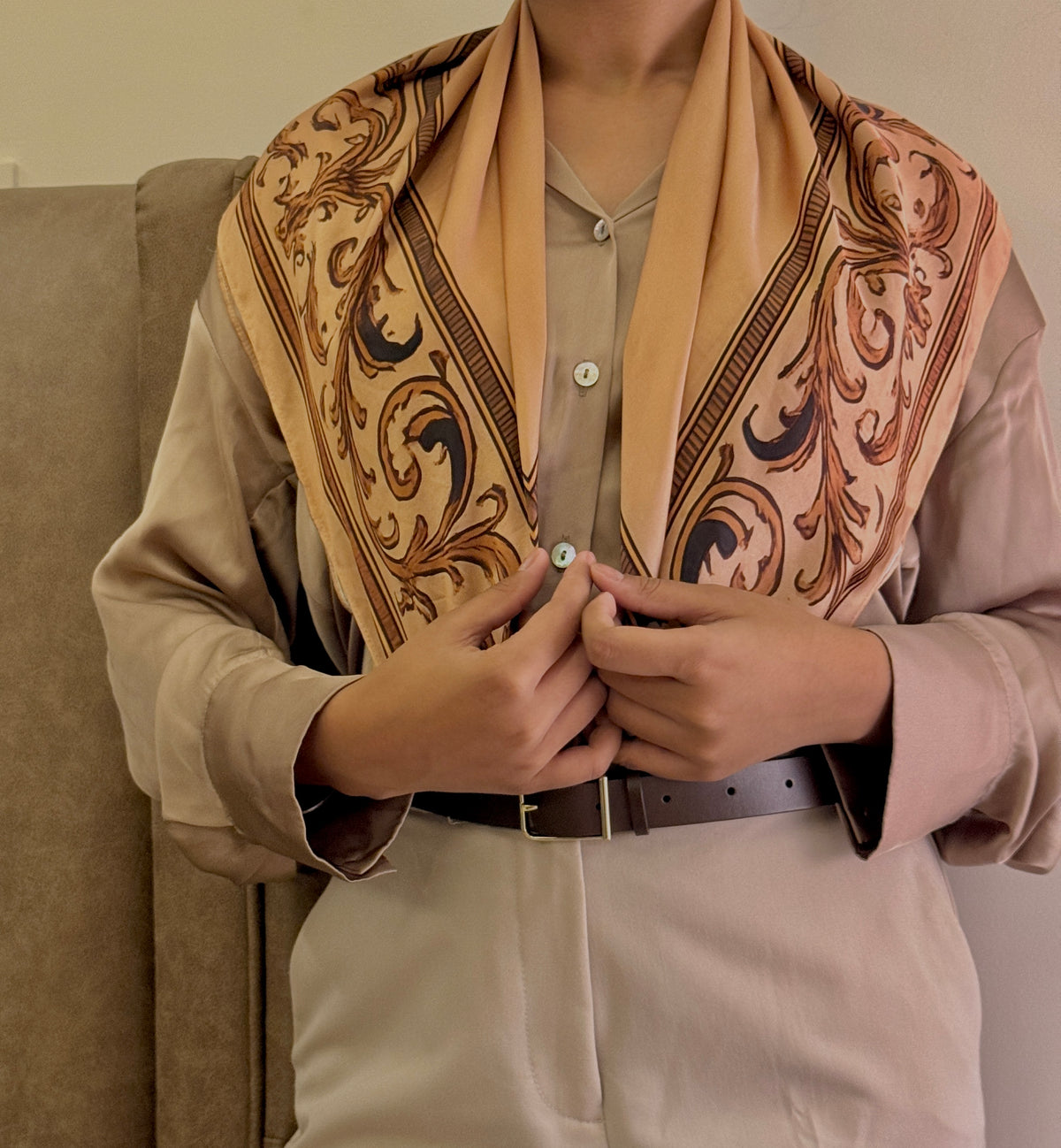 Person wearing a patterned scarf with a neutral background