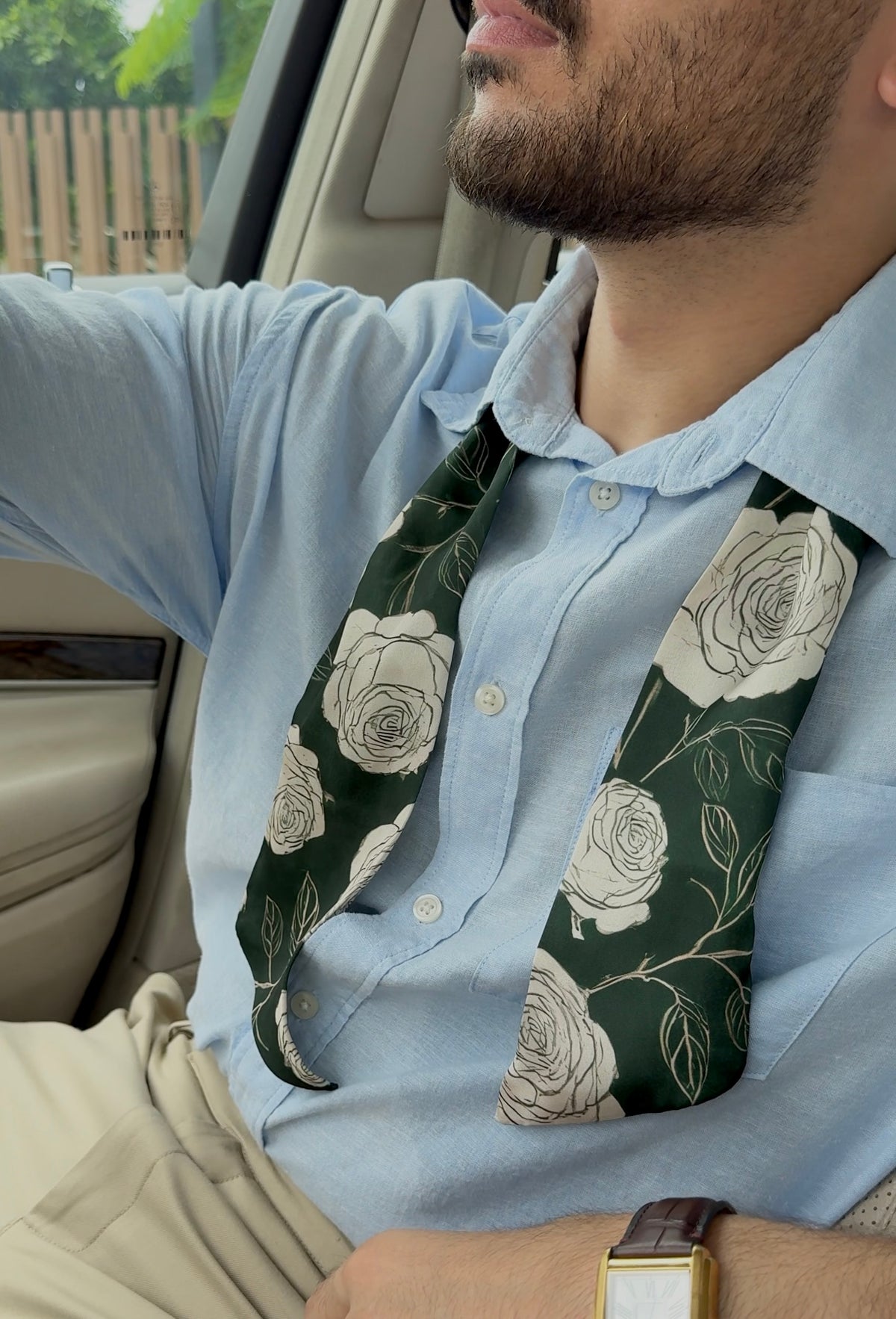 Man wearing a light blue shirt with a floral Scarf inside a vehicle