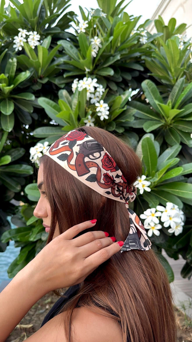 Woman with a decorative scarf in front of green foliage and white flowers