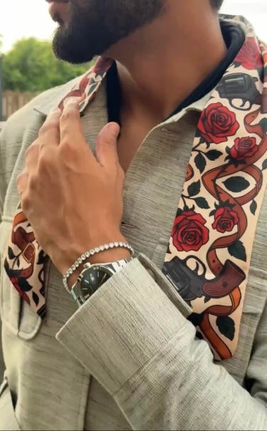 Person wearing a patterned scarf with roses and guns, adjusting it around their neck.