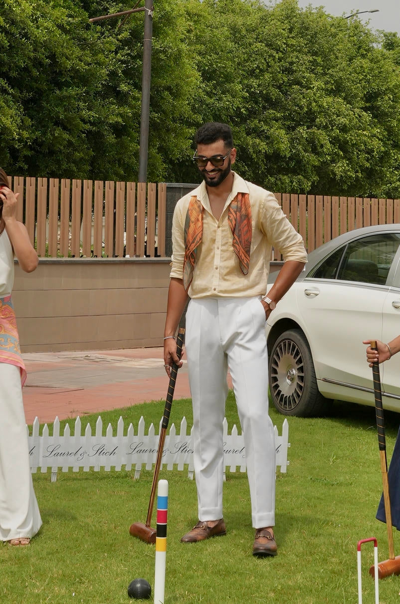 Man playing croquet in a garden wearing a scarf