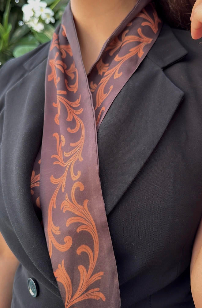 Person wearing a dark blazer with a decorative orange patterned scarf.